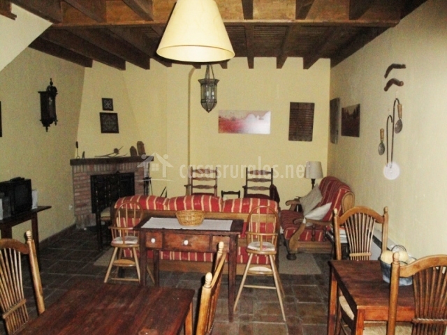 Salón con chimenea en la esquina y muebles de madera de la casa rural Salón con chimenea en la esquina y muebles de madera de la casa rural